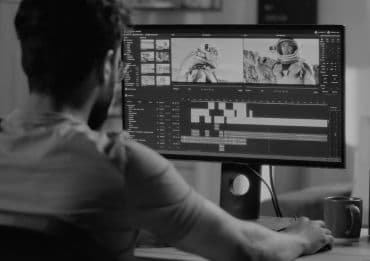 Mann schneidet Video an PC mit Hilfe von KI